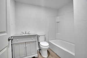 Full bathroom featuring washtub / shower combination, vanity, hardwood / wood-style flooring, and toilet