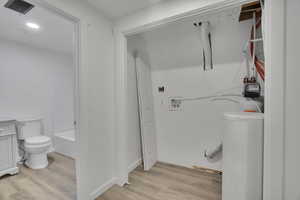 Bathroom with toilet, a bath, and hardwood / wood-style floors