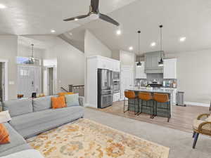 Living room with high vaulted ceiling, ceiling fan, light wood-type flooring, and sink