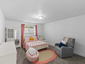 Bedroom with a textured ceiling and dark carpet