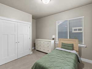 Carpeted bedroom with a textured ceiling, multiple windows, and a closet