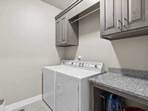 Laundry room with cabinets, light tile patterned floors, and separate washer and dryer