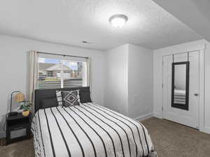 Carpeted bedroom featuring a textured ceiling and a closet