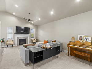 Carpeted living room with vaulted ceiling, ceiling fan, and plenty of natural light