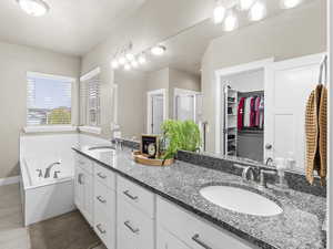 Bathroom featuring vanity, tiled bath, and tile patterned floors