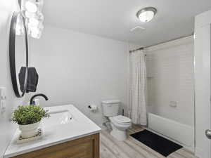 Full bathroom featuring shower / bath combo, toilet, hardwood / wood-style floors, a textured ceiling, and vanity