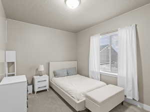 Bedroom with a textured ceiling and light carpet