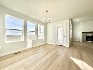 Interior space with a chandelier, a textured ceiling, light hardwood / wood-style floors, and a fireplace