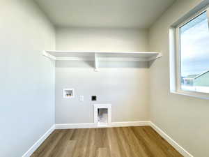 Laundry area with hookup for a washing machine, electric dryer hookup, a healthy amount of sunlight, and light hardwood / wood-style flooring