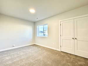 Unfurnished bedroom with light colored carpet and a closet