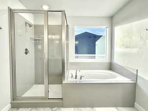 Bathroom with independent shower and bath, a textured ceiling, and a healthy amount of sunlight