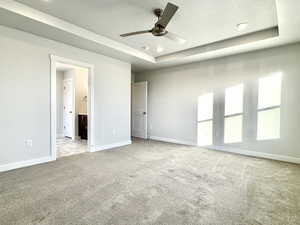 Carpeted spare room with ceiling fan and a tray ceiling