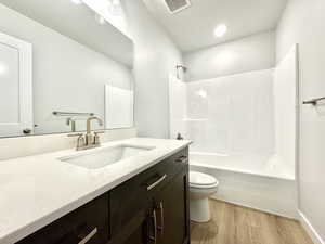 Full bathroom featuring wood-type flooring, toilet, vanity, and bathtub / shower combination