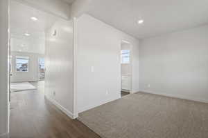 Empty room with beamed ceiling and dark wood-type flooring