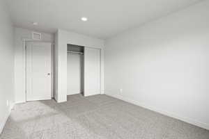 Unfurnished bedroom with light carpet and a closet