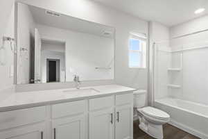 Full bathroom featuring hardwood / wood-style flooring, vanity, toilet, and washtub / shower combination