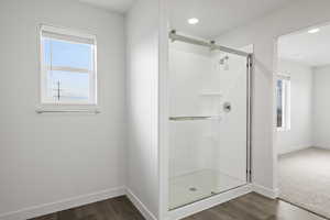 Bathroom with wood-type flooring and a shower with shower door