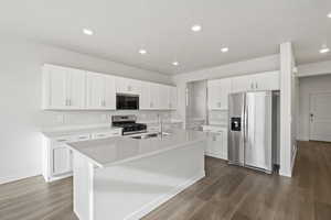 Kitchen featuring appliances with stainless steel finishes, dark wood-type flooring, sink, a center island with sink, and white cabinetry