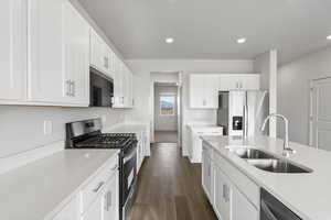 Kitchen featuring white cabinets, appliances with stainless steel finishes, dark wood-type flooring, and sink