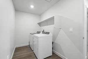 Laundry room featuring washing machine and clothes dryer and hardwood / wood-style flooring