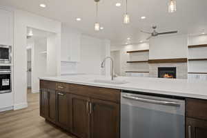 Kitchen featuring stainless steel appliances, white cabinetry, hanging light fixtures, and sink