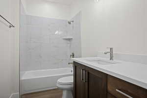 Full bathroom with tiled shower / bath, toilet, vanity, and hardwood / wood-style flooring