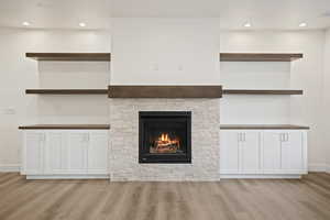 Unfurnished living room with light wood-type flooring and a stone fireplace