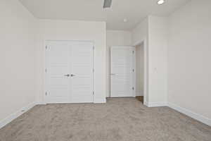 Unfurnished bedroom with a closet, ceiling fan, and light colored carpet