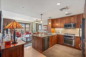 Kitchen featuring stainless steel appliances, hanging light fixtures, sink, kitchen peninsula, and light hardwood / wood-style flooring