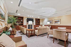 Carpeted living room featuring built in shelves and a tray ceiling