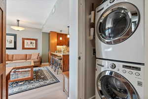 Clothes washing area with light hardwood / wood-style floors, sink, and stacked washer and clothes dryer