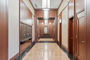 Corridor featuring ornamental molding, mail boxes, a package area, and a high ceiling