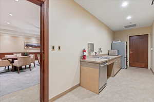 Kitchen featuring light colored carpet, sink, and appliances with stainless steel finishes