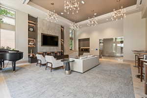 Living room featuring a high ceiling, light wood-type flooring, a tray ceiling, and plenty of natural light