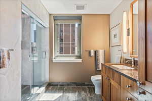 Bathroom with vanity, hardwood / wood-style flooring, toilet, and a shower with door