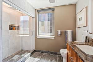 Bathroom with hardwood / wood-style floors, vanity, toilet, and an enclosed shower