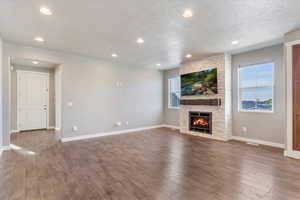 Great room featuring hardwood / wood-style flooring, and a stacked-stone fireplace with custom mantel