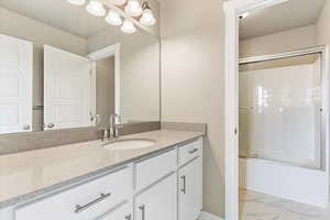 Bathroom featuring vanity and enclosed tub / shower combo