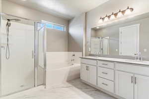 Bathroom featuring shower with separate bathtub, dual sinks