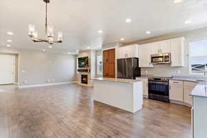 Kitchen with white cabinets, appliances with stainless steel finishes, light hardwood / wood-style flooring, and dining area