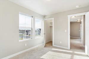 Unfurnished bedroom featuring a textured ceiling, a walk in closet, light colored carpet, and a closet