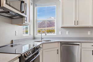 Kitchen with a mountain view, white cabinets, appliances with stainless steel finishes, and corner sink