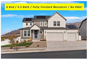 View of front of home with a mountain view, a garage, and solar panels