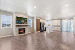 Unfurnished living room with lots of natural light, wood-type flooring, and a stone fireplace