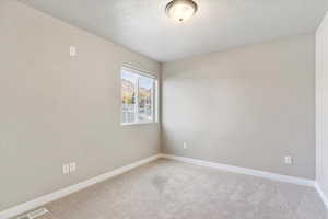 Carpeted spare room featuring a textured ceiling