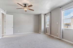 Carpeted main bedroom with ceiling fan and a textured ceiling