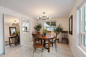 Dining room with light hardwood / wood-style flooring, an inviting chandelier, and crown molding