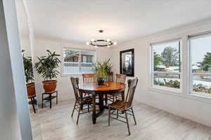 Dining space with light wood-type flooring, an inviting chandelier, and crown molding