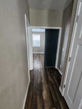 Corridor with lofted ceiling, dark hardwood / wood-style flooring, and a textured ceiling