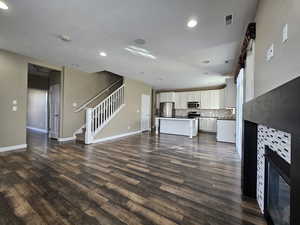 Unfurnished living room with a fireplace, dark wood-type flooring, and sink